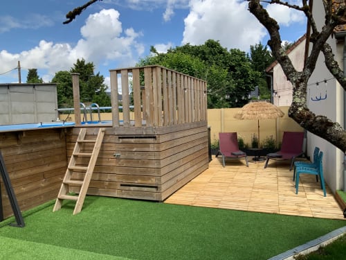 Blois cottage garden with wooden deck, loungers, umbrella, and heated pool area surrounded by green space