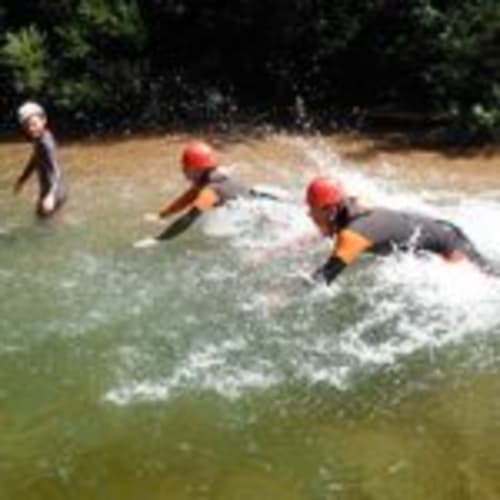 Whitewater rafting adventure in Girona with red helmets and orange life jackets on river