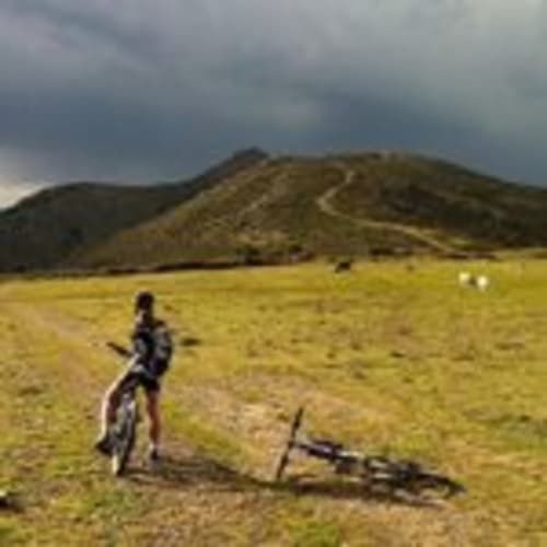 Mountain biker resting in green valley with hills, Empordà countryside near Can Gat Vell in Girona