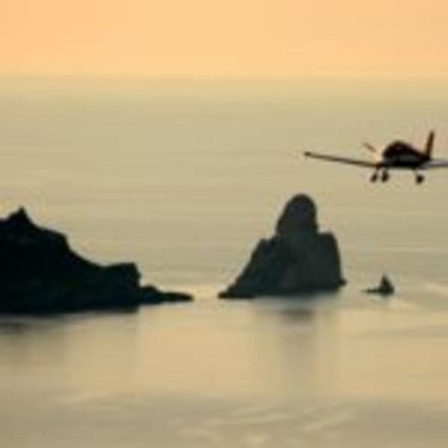 Seaplane flying over rocky coastal formations near Can Gat Vell, Empordà, Girona
