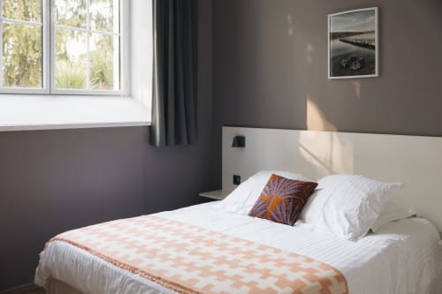 Chambre moderne à La Maison D'olivier avec literie blanche, jeté pêche, murs bicolores et large baie vitrée donnant sur les jardins