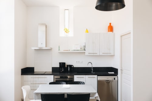Cuisine minimaliste moderne à La Maison D'olivier BnB à Mesnard La Barotière avec plan de travail noir et mobilier blanc