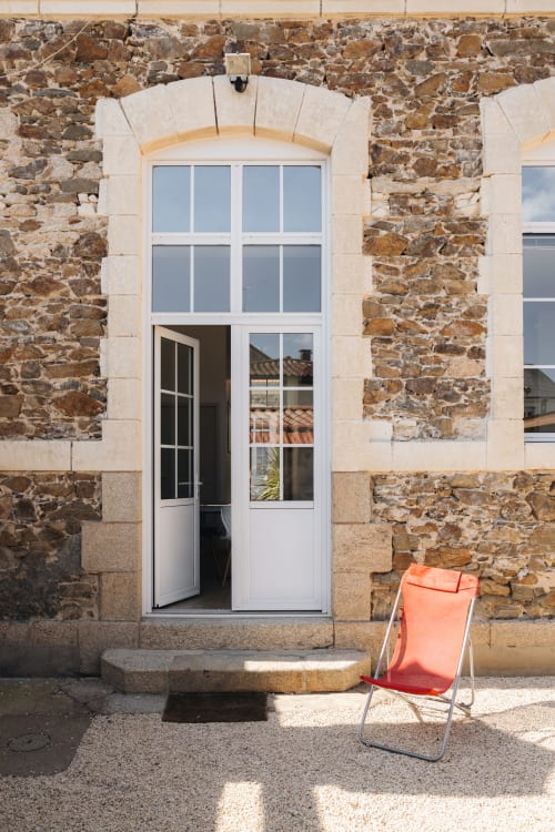 Porte blanche avec fenêtre cintrée sur façade en pierre rustique à La Maison D'olivier B&B à Mesnard La Barotière, France