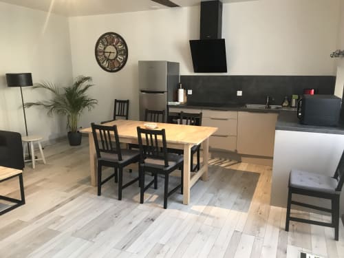Modern kitchen-dining area at Chablis Appart with wooden table, black chairs, stainless appliances, and clock
