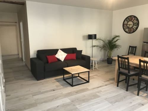 Salon moderne de la Chambre 4 Chablis Appart avec canapé noir, table à manger, parquet et vue sur la ville