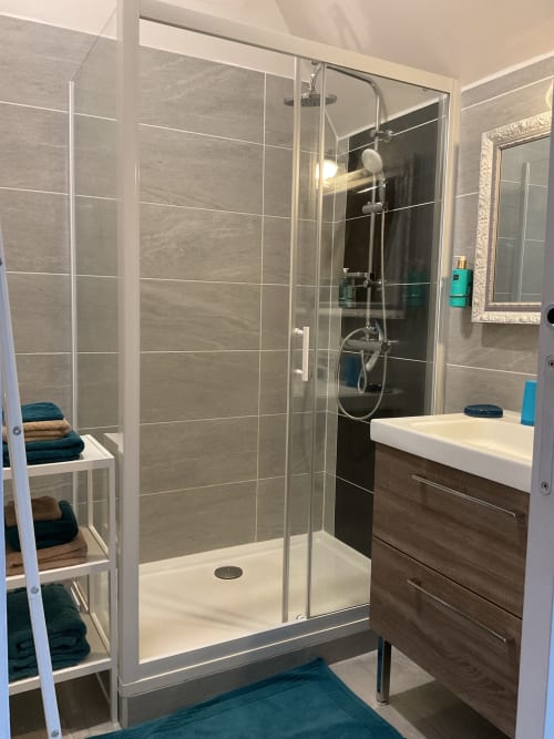 Douche moderne vitrée avec serviettes soignées, salle de bain maison d’hôtes à Evry, Essonne, France, propreté, confort, ambiance apaisante