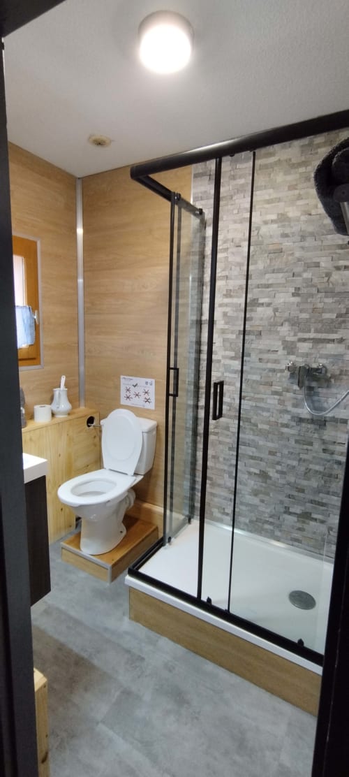 Modern bathroom at L'étape Du Fanfoué with walk-in shower, toilet, and wooden finishes in Chamrousse