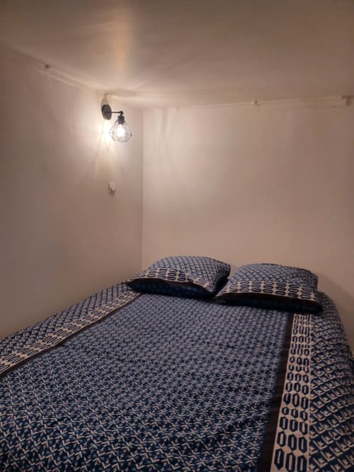 Chambre moderne de l'appartement Accolade à Châteaudun avec literie motif bleu et luminaire mural