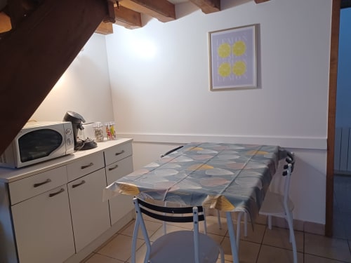 Kitchenette cosy à l'hôtel Accolade à Châteaudun avec micro-ondes, lit et tableau citronné.
