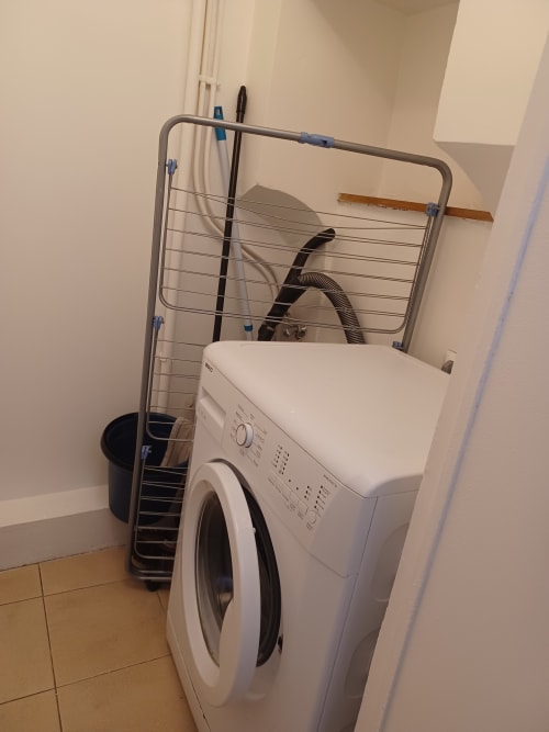 Lave-linge blanc avec étendoir dans l'espace buanderie de l'appartement Accolade, Châteaudun