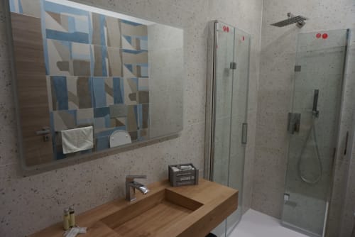 Bagno moderno con lavabo in legno, ampio specchio, box doccia in vetro e pareti con piastrelle maculate a La Dimora Di Ipno