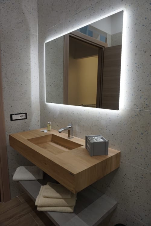 Bagno moderno con lavabo in legno, specchio illuminato e pareti in cemento a La Dimora Di Ipno a Vallata