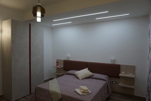 Camera moderna a La Dimora Di Ipno a Vallata con letto matrimoniale, testata marrone, arredamento minimalista e luci LED al soffitto.