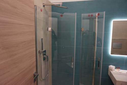 Bagno moderno con piastrelle turchesi, box doccia in vetro e specchio illuminato presso La Dimora Di Ipno a Vallata