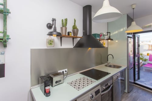 Cocina moderna del apartamento Wehost Costaluz en Puerto Santa María, con encimeras de acero inoxidable y lámparas colgantes negras