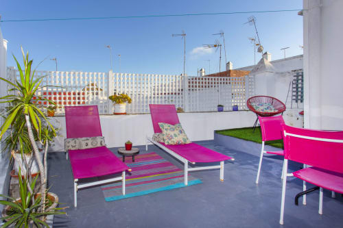 Terraza con vista a la ciudad y tumbonas rosas en el apartamento Wehost Costaluz, Puerto Santa María