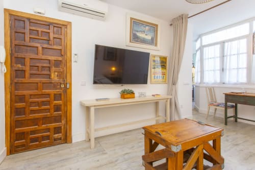 Luminoso estudio en Puerto Santa María con puerta de madera, TV, escritorio y mesa de madera en la sala de estar