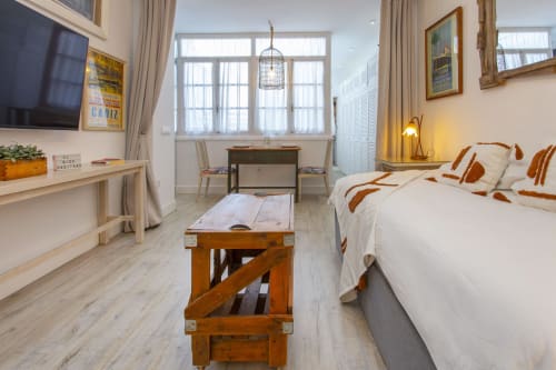 Moderno estudio en Puerto Santa María con cama, escritorio, televisión, muebles de madera y ventanas luminosas