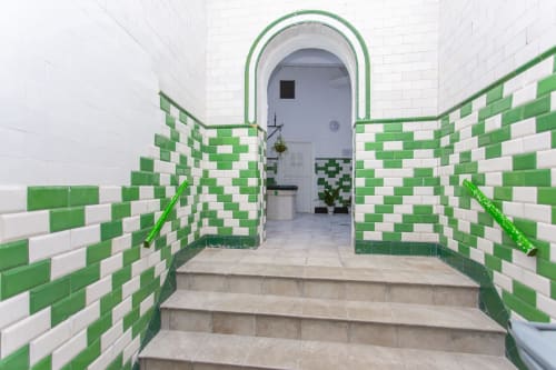 Pasillo con azulejos a cuadros verde y blanco, con puerta arqueada en Wehost Costaluz, Puerto Santa María
