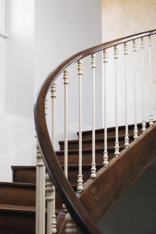 Élégant escalier en bois aux courbes élancées et à la rampe ornée de balustres à La Maison D'olivier, boutique hôtel de Mesnard La Barotière