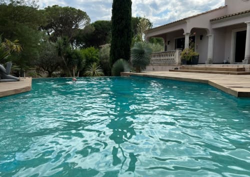 Türkisfarbenes Schwimmbad mit Holzterrasse und weiße Villa mit mediterranem Garten in La Conciergerie De Franck