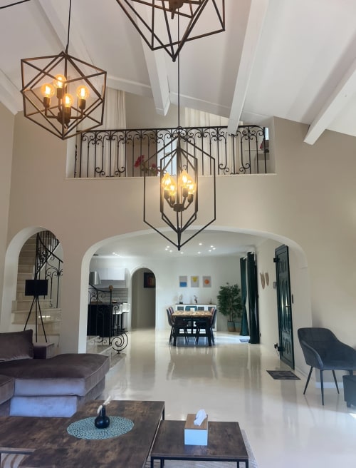 Modernes Villeninterieur mit zweistöckigem Foyer, geometrischen Pendelleuchten, Bogentüren und Essbereich im La Conciergerie De