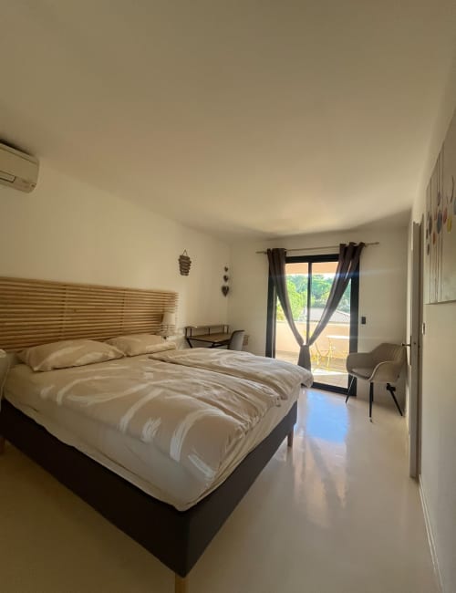 Geräumiges modernes Schlafzimmer in der Villa La Conciergerie De Franck mit Königinnenbett, Balkon mit Gartenblick und Sitzbereich