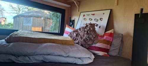Cozy cottage bedroom with pillows and blankets overlooking garden at Les Refuges Du Chalet, Jalhay