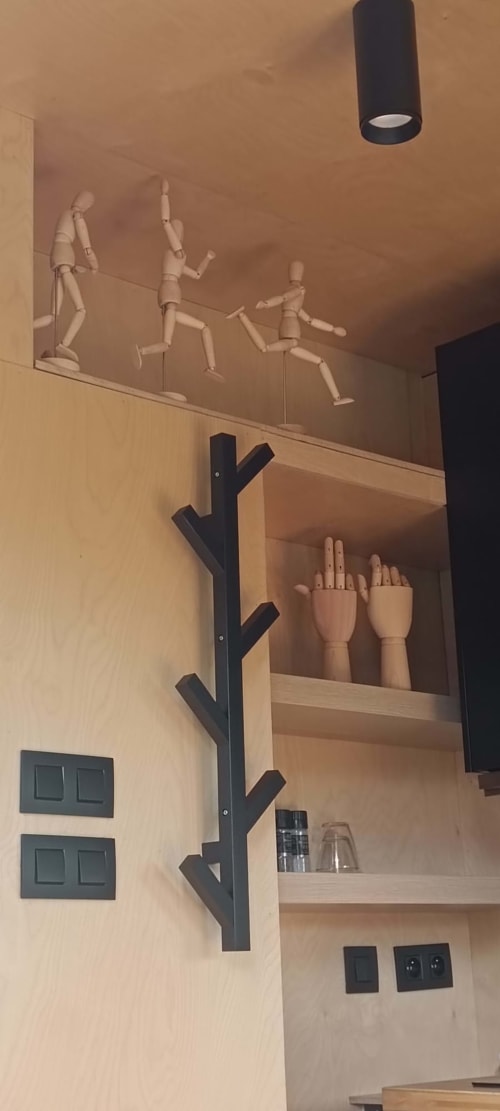 Wooden display shelf with black frame holding decorative wooden hand models and figurines at Les Refuges Du Chalet