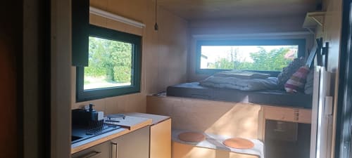 Cozy cottage interior at Les Refuges Du Chalet with kitchenette, loft bed, windows overlooking garden in Jalhay