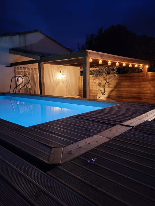 Espace piscine contemporain de la Suite Romantique à Cabannes avec pergola en bois éclairée et terrasse au crépuscule