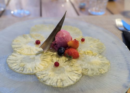 Élégant dessert dressé au Maquis Plage : tranches d'ananas, mousse de fruits rouges, baies fraîches et garniture chocolat