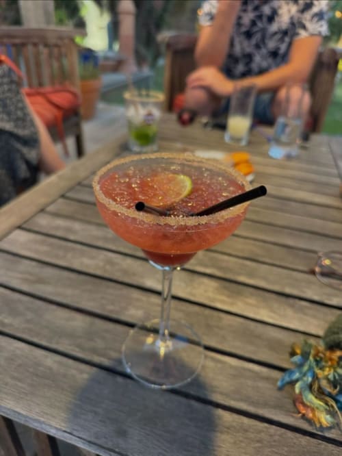 Cocktail coloré aux bords de sucre et garnison de citron vert sur la terrasse extérieure du Maquis Plage à Poggio-Mezzana