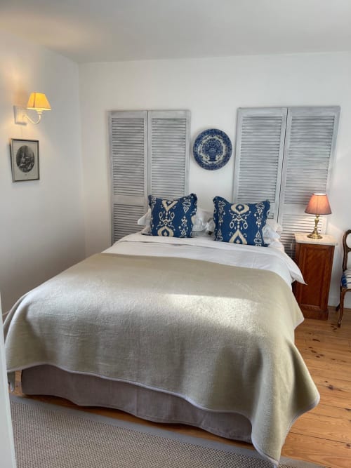 Chambre cosy au Manoir De Rieuzal à Loubressac avec coussins à motifs bleus, literie crème et décoration côtière