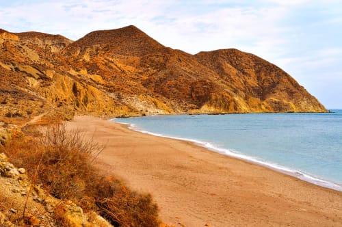 Acantilados dorados y playa de arena en Carboneras, España cerca del Hostal Juan Carlos