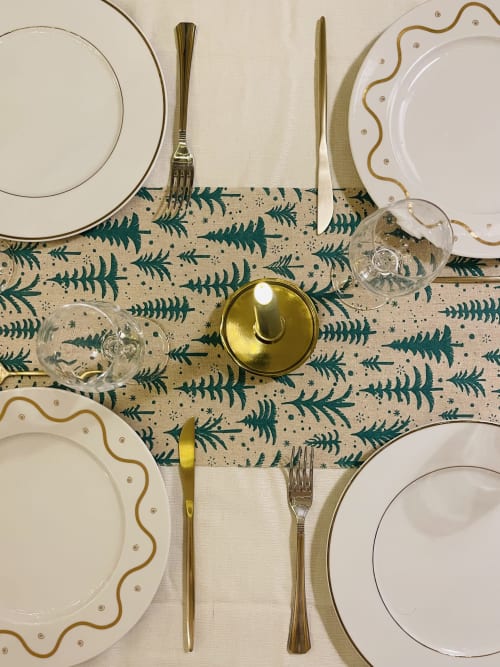 Mise de table élégante à La Maison George avec assiettes à bordure dorée, chemin de table en sapin et chandelier en laiton