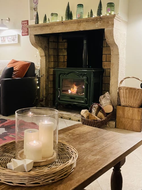 Salon douillet avec foyer à La Maison George : poêle vert, bougies et décor rustique à Flavigny-sur-Ozerain