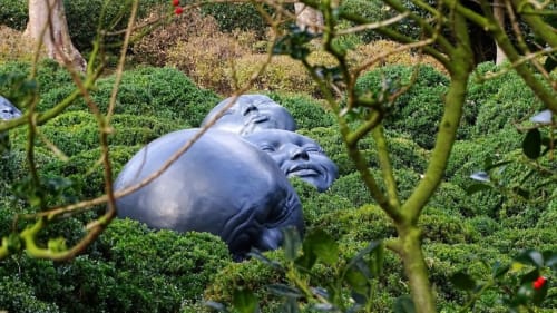 Blue sculptural head surrounded by green topiary hedges at Villa Eliane guesthouse in Étretat