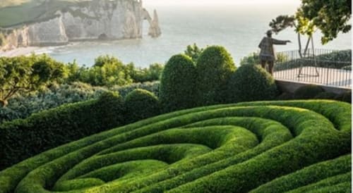 Manicured hedge maze garden at Villa Eliane with Étretat cliffs and sea view in background