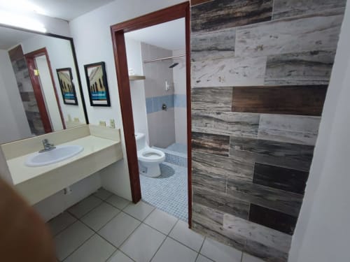 Baño del Hotel Estrella en Matamoros con azulejos tipo madera en ducha, vanidad y espejo