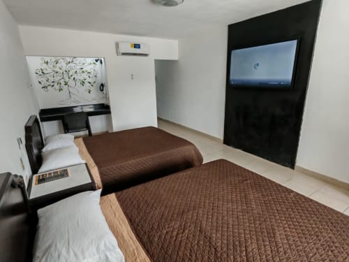 Habitación del Hotel Estrella en Matamoros con dos camas, TV, pizarrón y aire acondicionado
