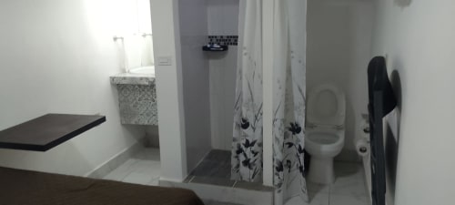 Baño moderno del Hotel Estrella en Matamoros con inodoro, lavabo y cortina de ducha decorativa