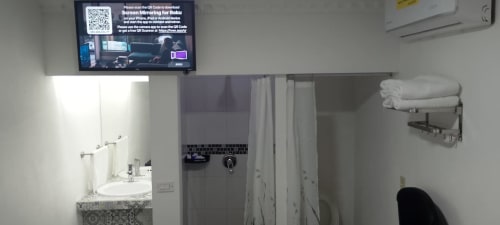Baño del Hotel Estrella en Matamoros con lavamanos, ducha, toallas y TV mostrando instrucciones de streaming