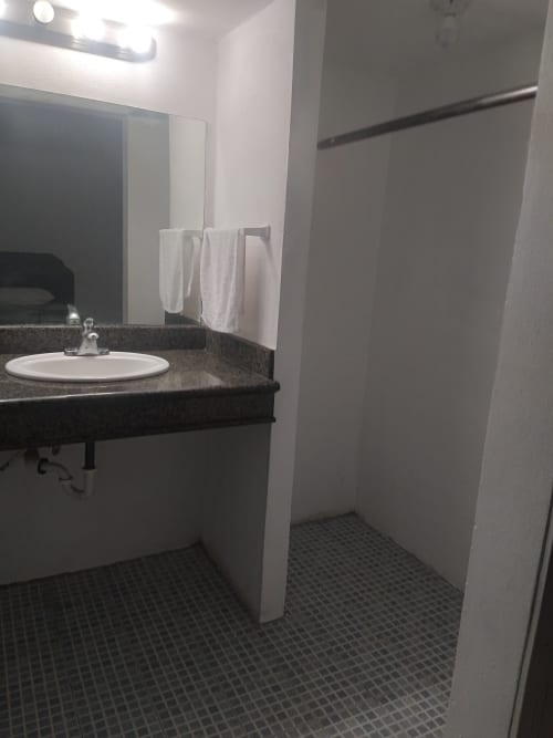 Baño moderno del Hotel Estrella en Matamoros con lavabo redondo, espejo de tocador y área de ducha