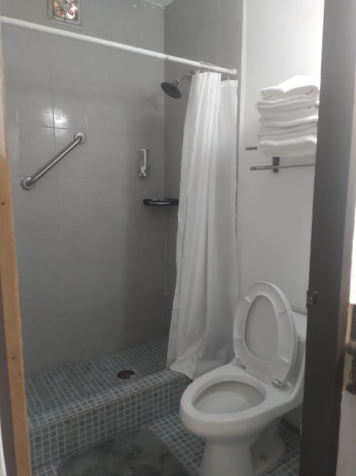 Baño limpio en Hotel Estrella, Matamoros, con ducha tipo caminable, inodoro blanco, piso de azulejos y toallero
