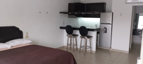 Habitación del Hotel Estrella en Matamoros con cama, cocina equipada con electrodomésticos de acero inoxidable y barra.