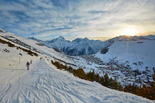 Snowy ski slope at Montgenèvre with alpine village and snow-covered mountains at sunset