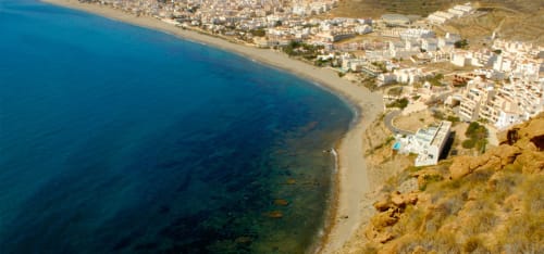 Vista aérea de la playa de Carboneras y pueblo costero con aguas turquesas del Mediterráneo y edificios blancos