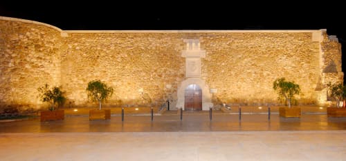 Exterior de fortaleza de piedra histórica en Hostal Juan Carlos de Carboneras, iluminada de noche con entrada al patio