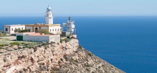 Faro del Hostal Juan Carlos encaramado en acantilado rocoso con vistas al mar Mediterráneo en Carboneras, España
